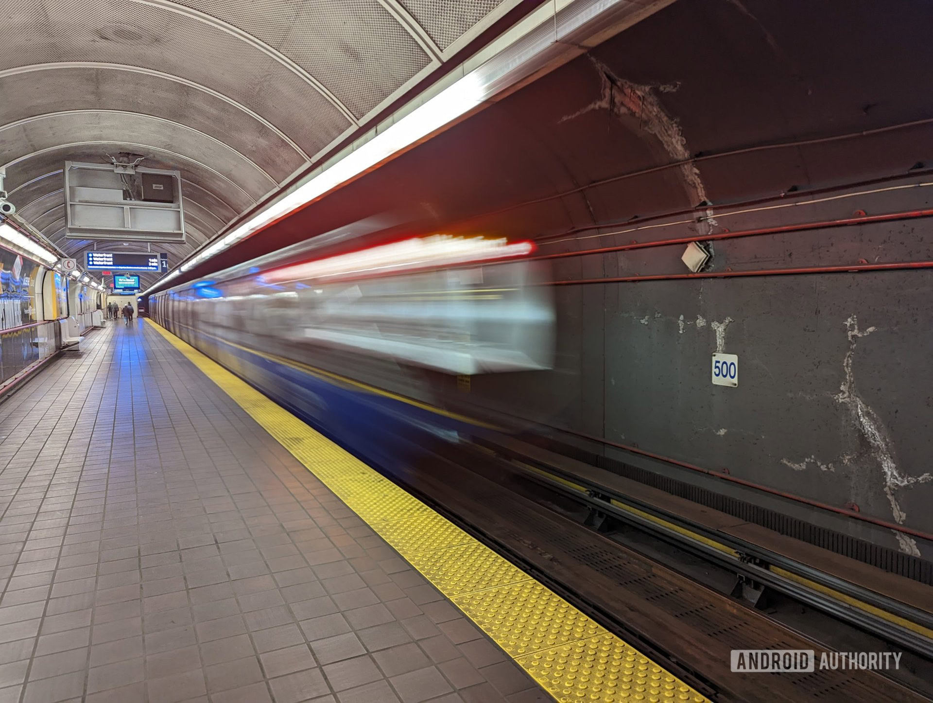 A Long Exposure shot taken with a Google Pixel 6 of a subway car. The subway car itself is blurry and conveys a sense of motion while the tunnel and station platform are clear.