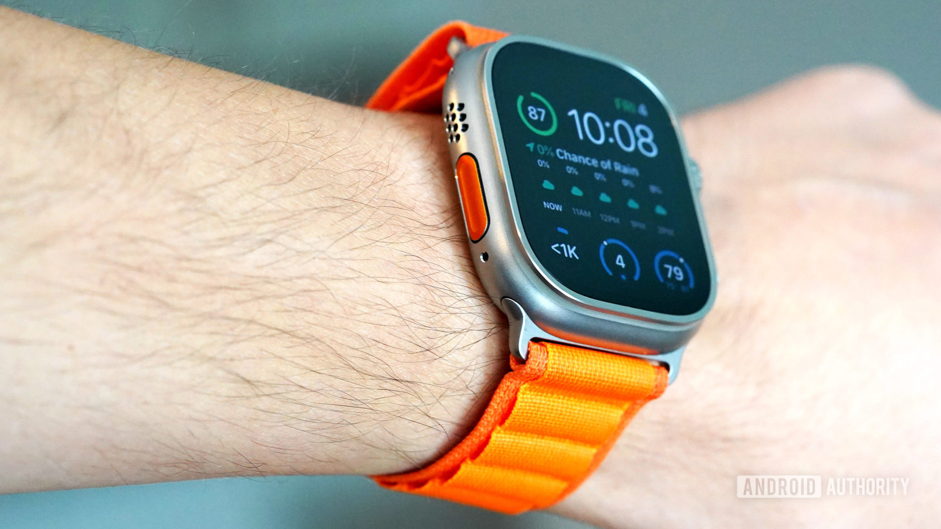 An Apple Watch Ultra on a user's wrist features an orange Action button.
