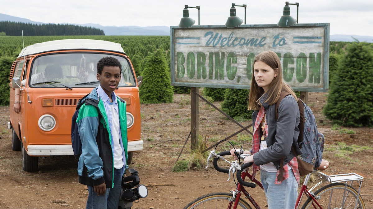 Two kids in front of a sign for the town of Boring, Oregon, in Everything Sucks! - best hidden gems on Netflix