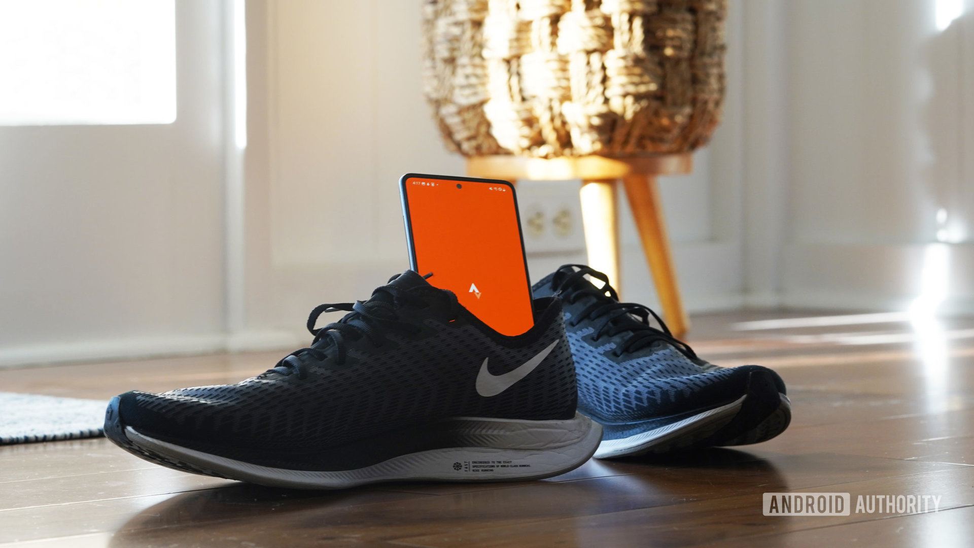 A Galaxy A51 rests in a running sneaker, displaying the Strava app logo.