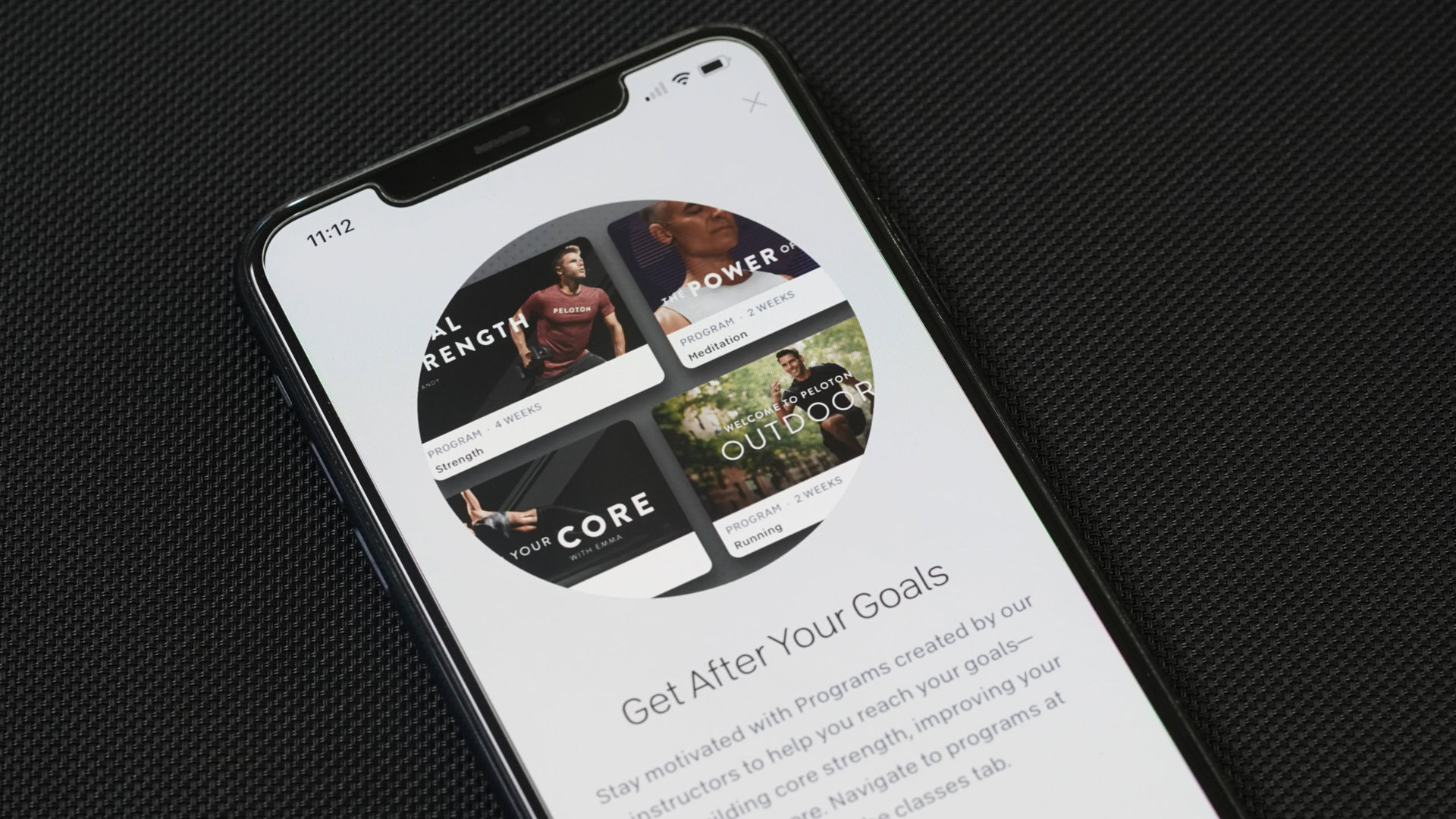 An iPhone 11 displays the Programs screen of the Peloton App.