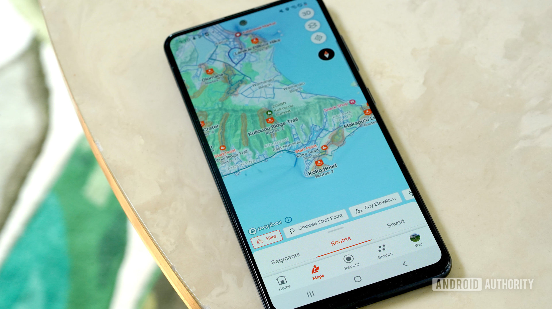 Galaxy A51 bertumpu pada meja marmer yang menampilkan tab Strava Maps pengguna.