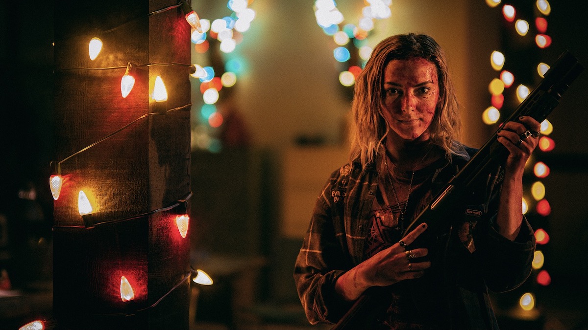 A bloodied woman holds a rifle surrounded by Christmas lights in Christmas Bloody Christmas