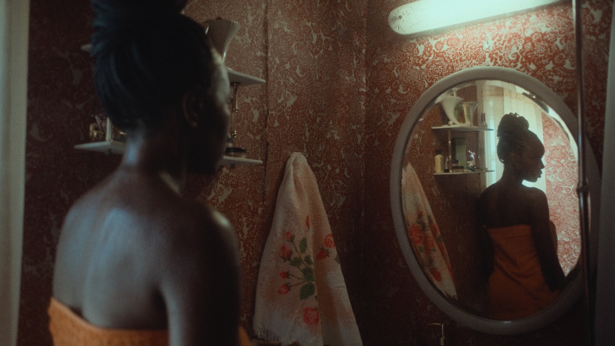 Anna Diop looks into a mirror, her reflection looking away in Nanny - underrated streaming movies of 2022