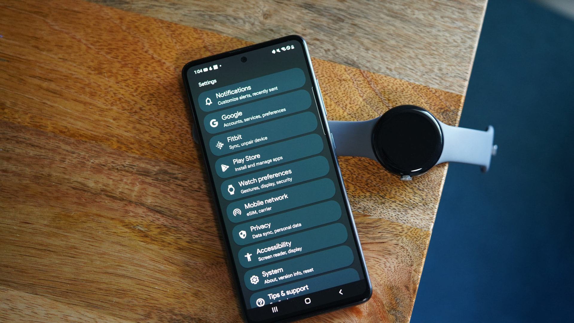 The Galaxy A51 displays the Settings menu in the Pixel Watch app.