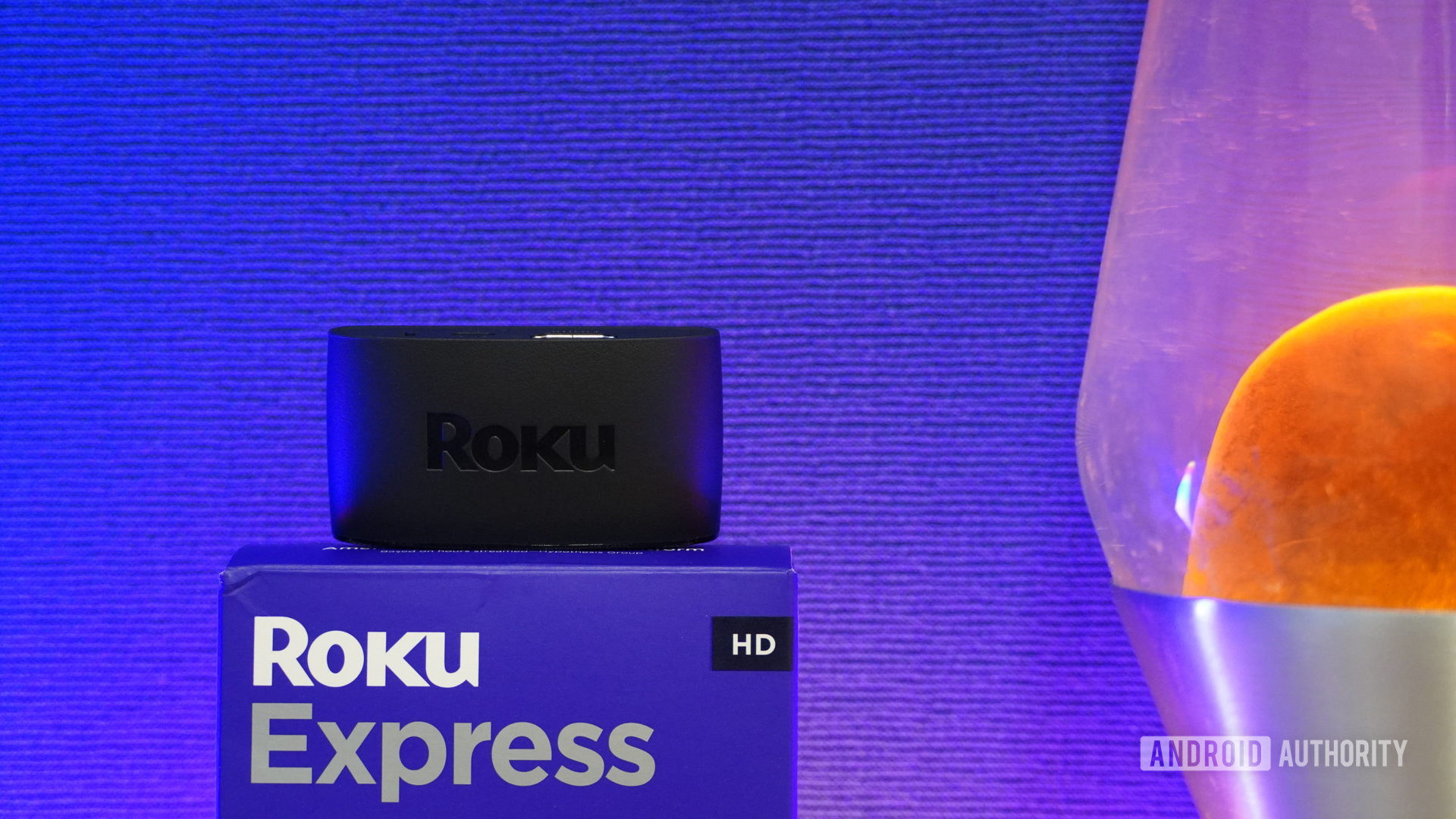 Roku Express sitting on box with lava lamp