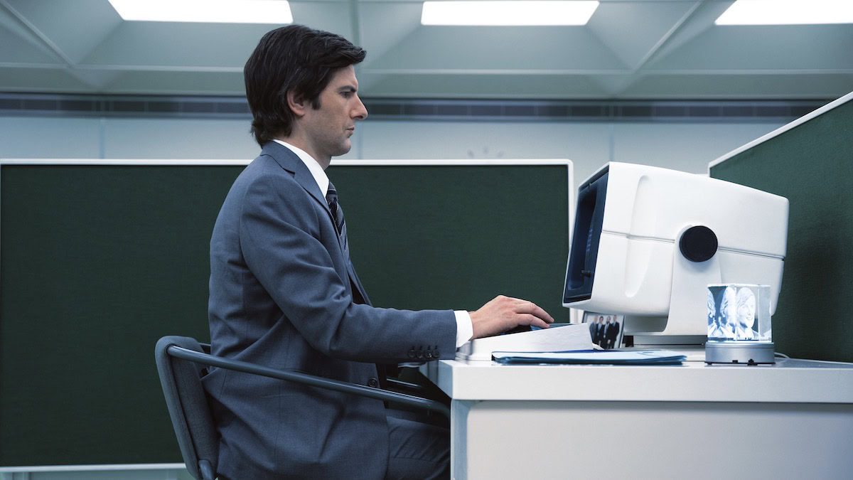 Adam Scott sits at a computer terminal in Severance