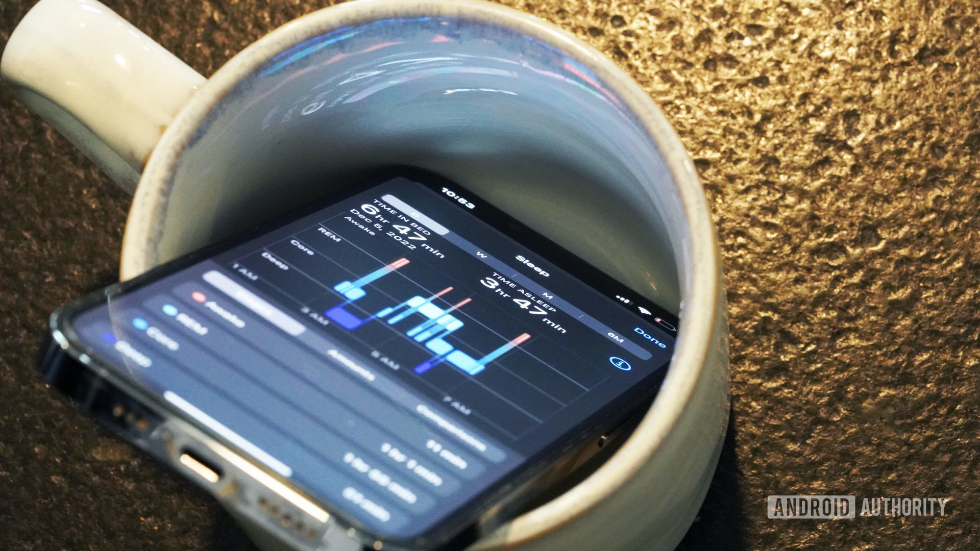 An iPhone in a coffee mug displays user sleep deprivation data.