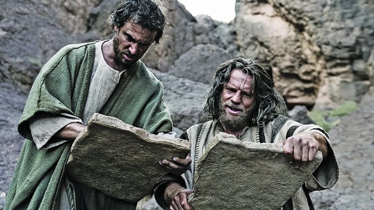 Two men look at stone tablets in The Bible