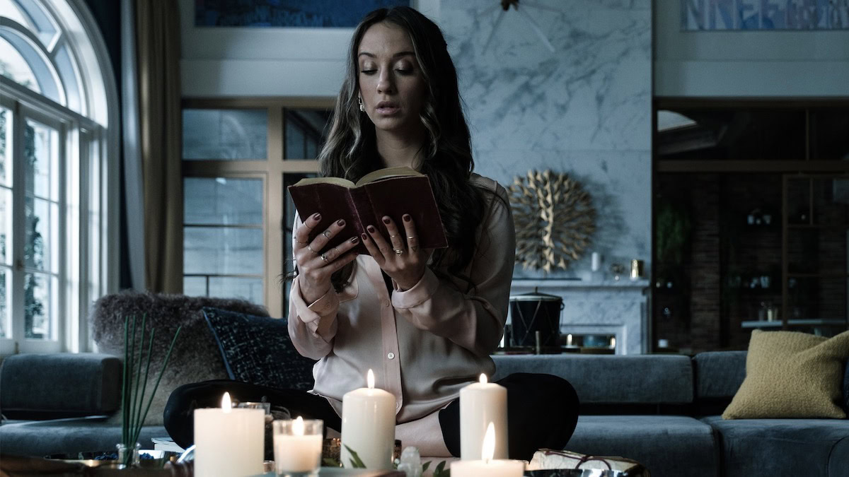 A woman reading from an ancient book surrounded by candles in The Magicians - appears as His Dark Materials