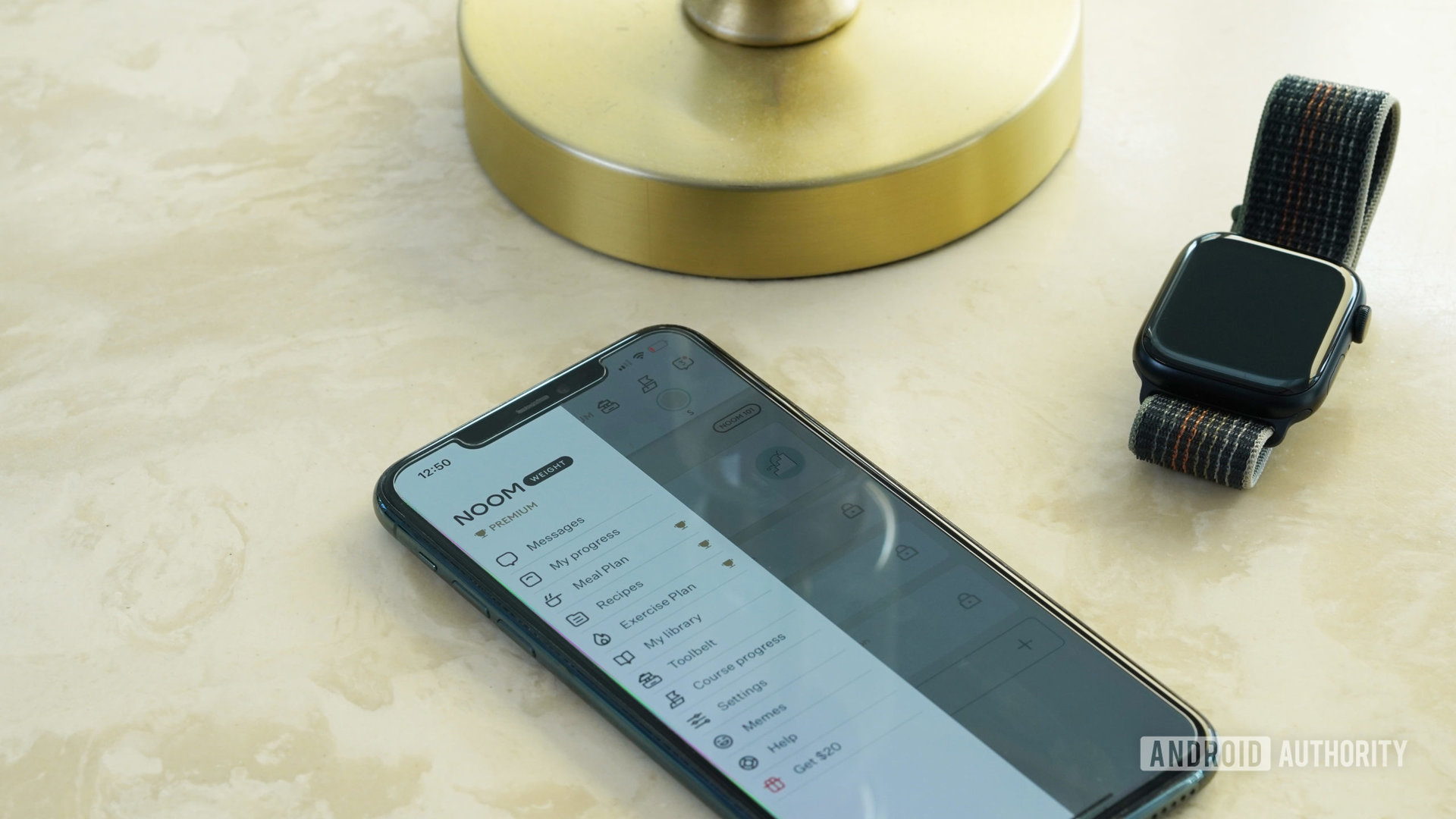 An iPhone 11 Pro resting on a marble table displays the Noom app.