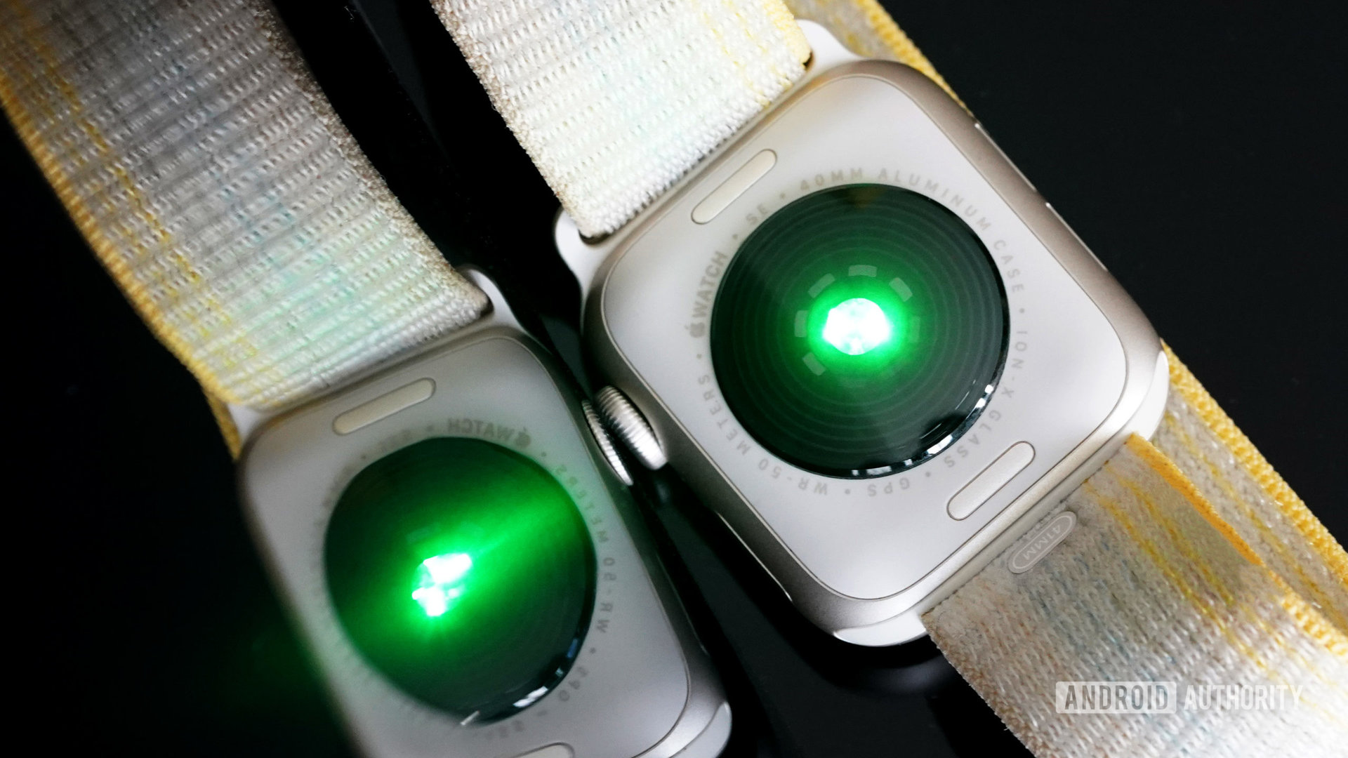 An Apple Watch SE 2 rests face down, flashing green LED lights.