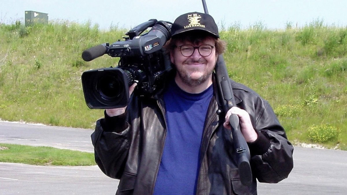 Michael Moore holds a camera and a gun in Bowling for Columbine