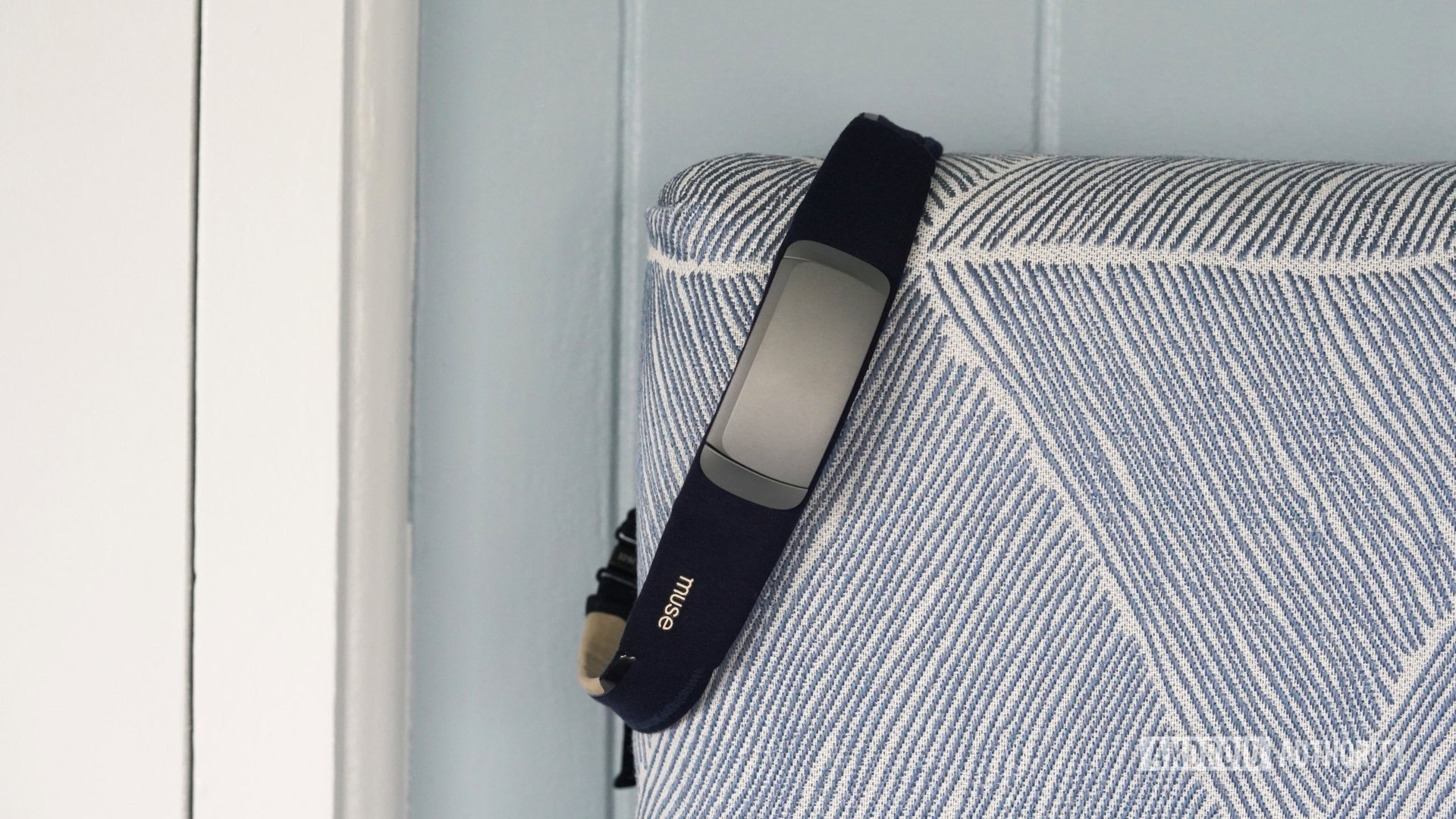 A Muse S Gen 2 headband hangs from a user's headboard.