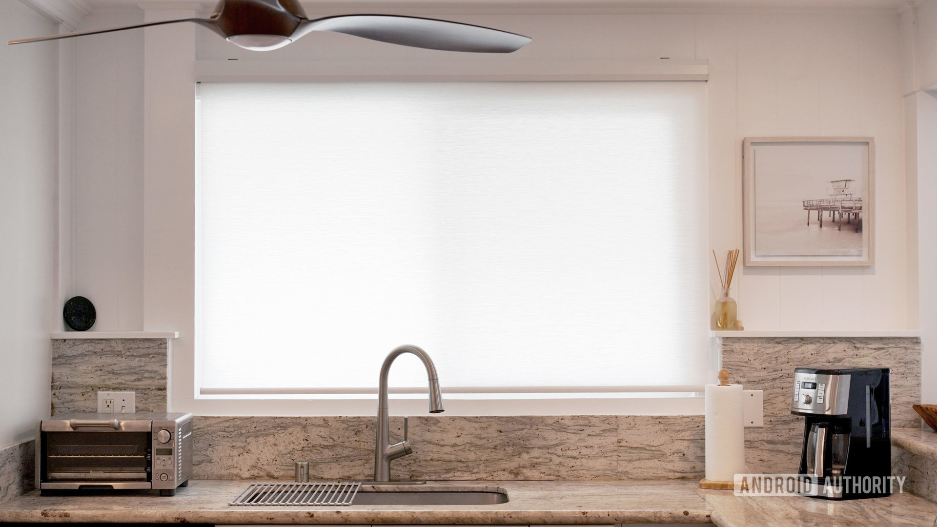A partial sheer smart blind lets sunlight into a kitchen while allowing for privacy.