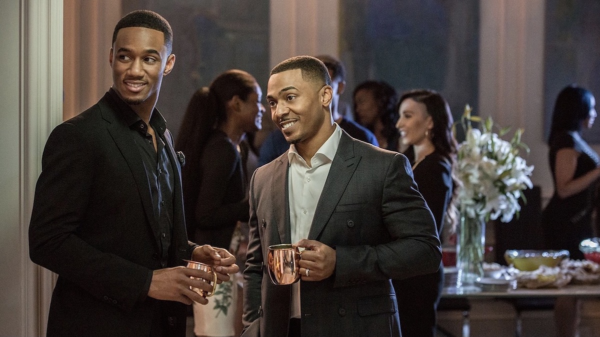 Two men hold drinks at a social event in Survivor's Remorse