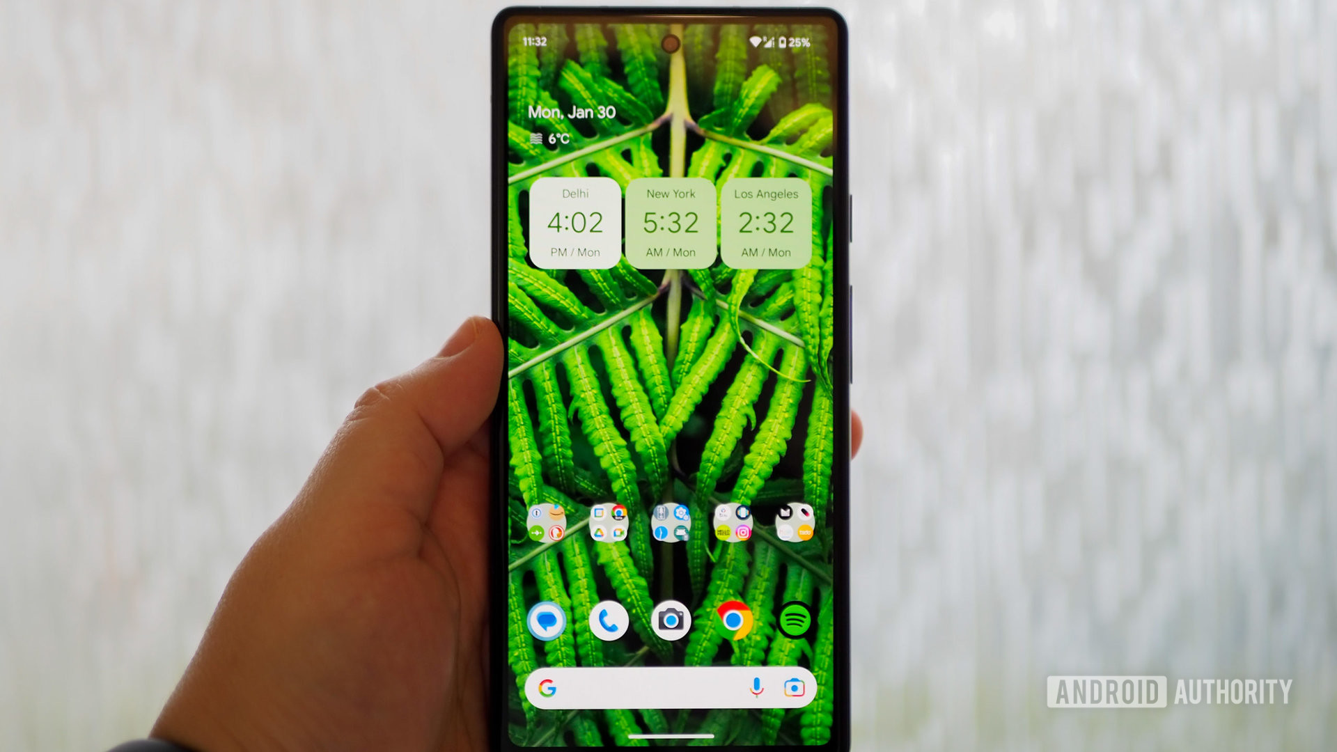 Google Pixel 6a in hand, display on, showing the homescreen
