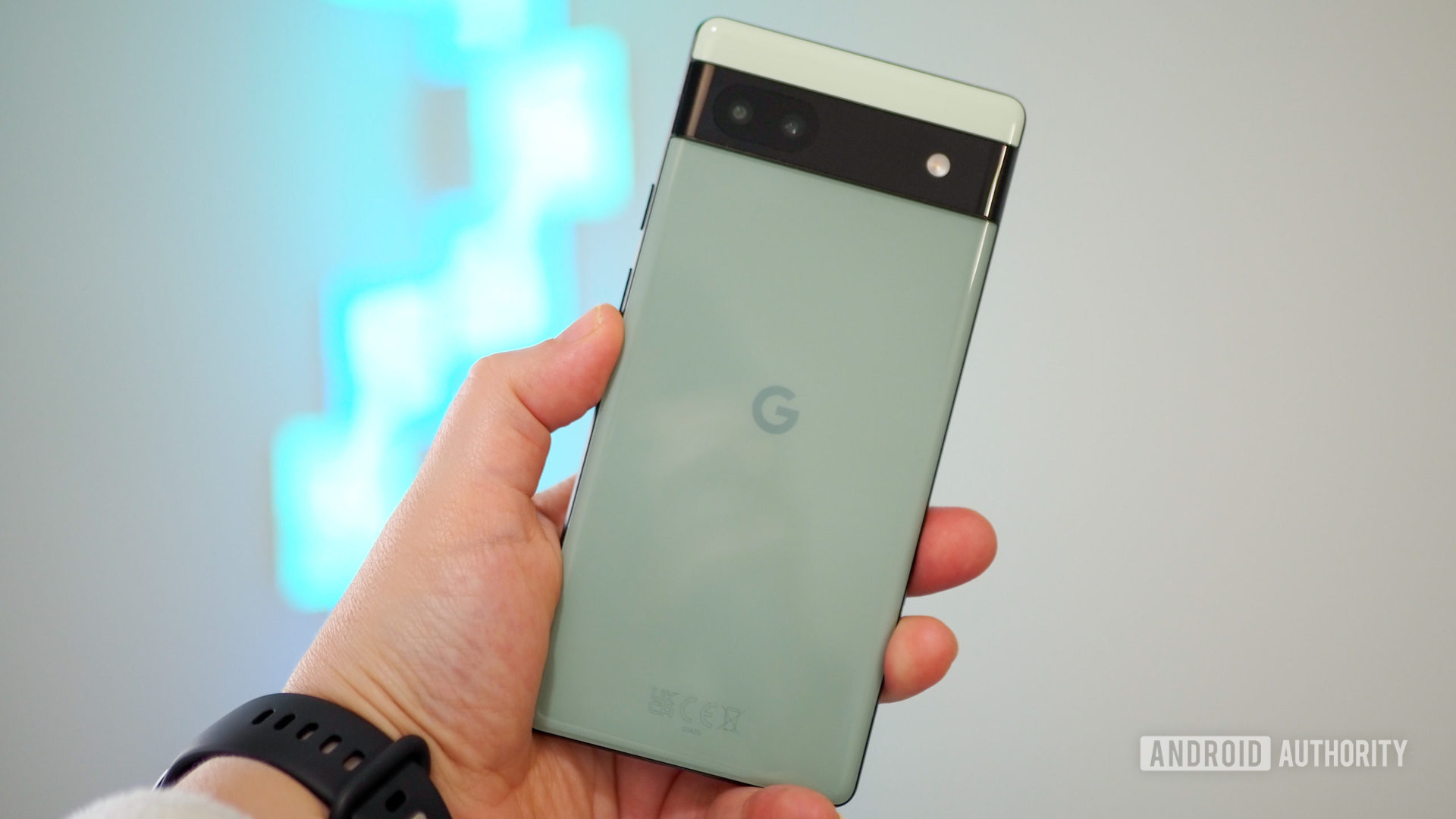 Google Pixel 6a in Sage color in hand, seen from the back