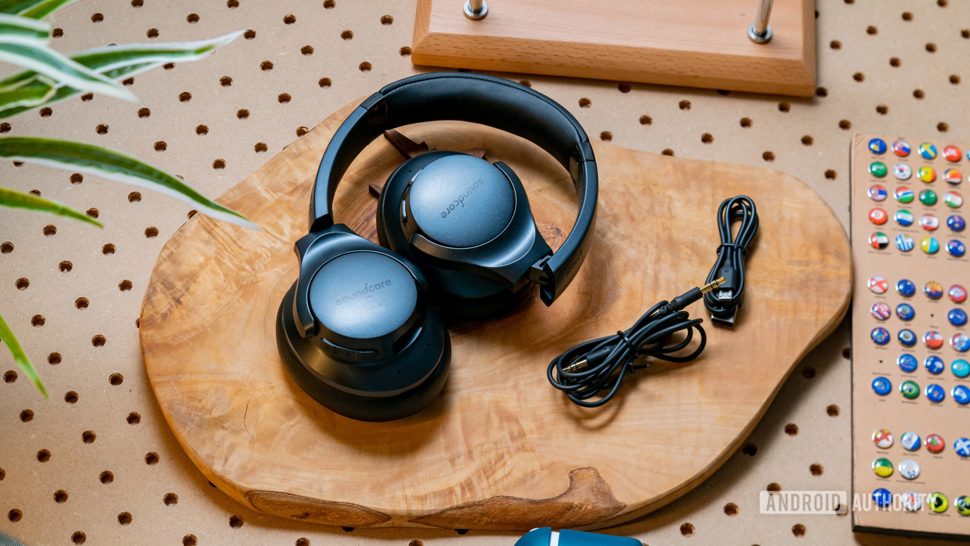 The Anker Soundcore Life Q20 wireless noise cancelling headphones folded up on a wooden surface next to the included cables.