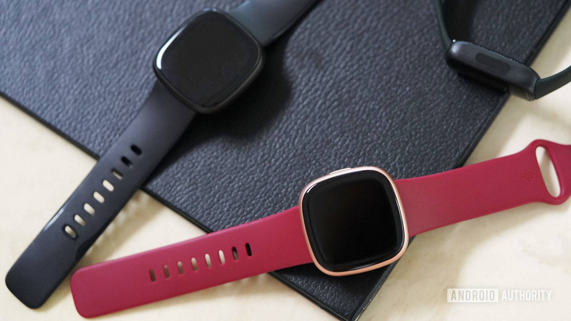 A variety of Fitbit devices rest on a table.