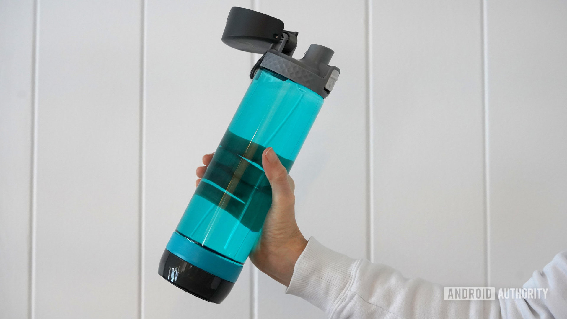 A smart bottle water user holds a HidrateSpark Pro Lite in hand.