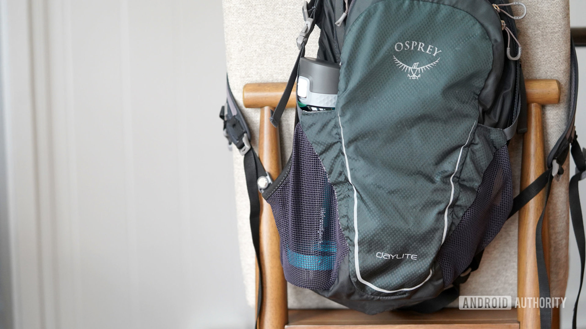 A HidrateSpark smart water bottle tucks into the side of a user's backpack.