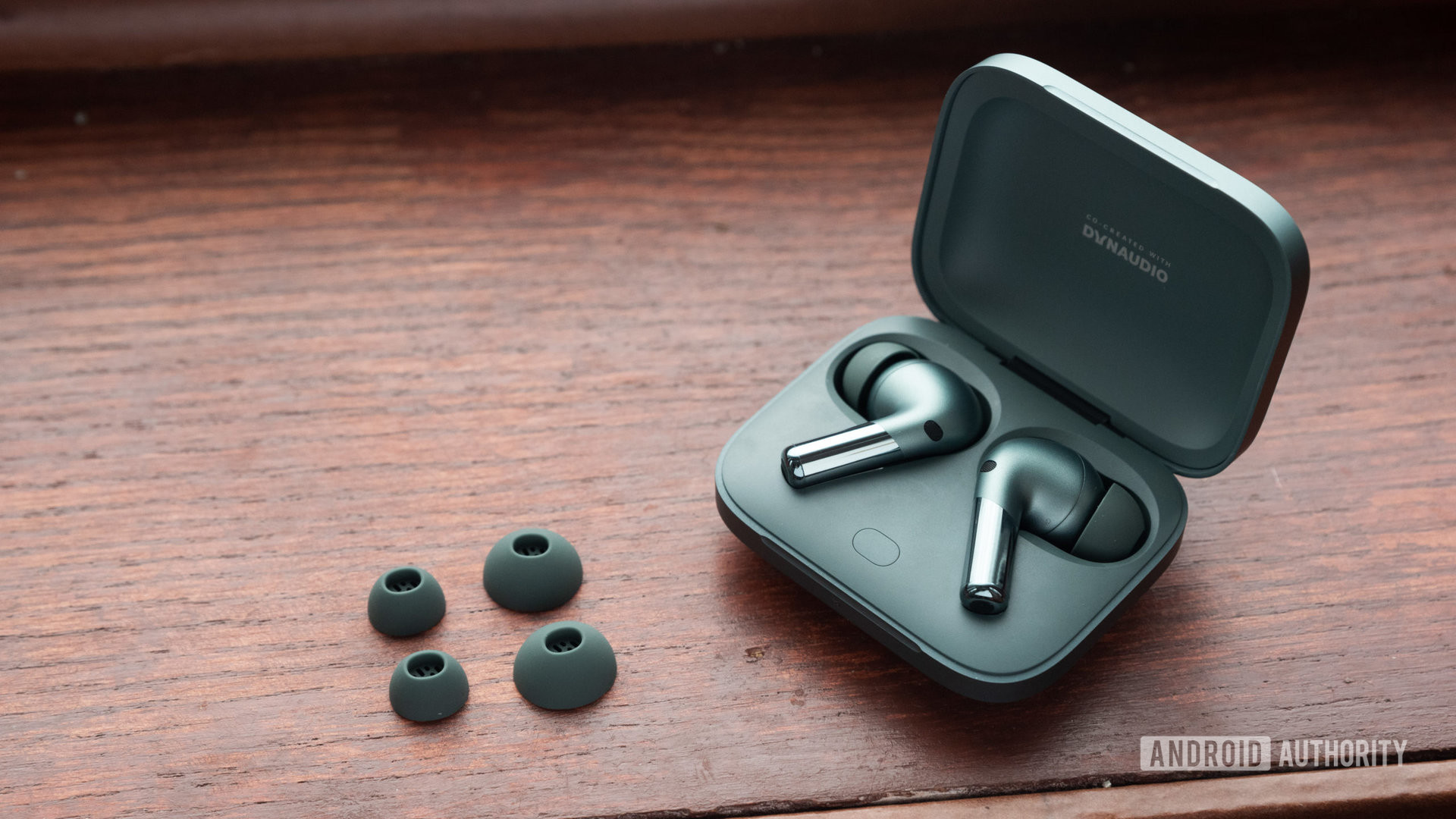 The OnePlus Buds Pro 2 noise cancelling wireless earbuds and ear tips on a wooden surface.