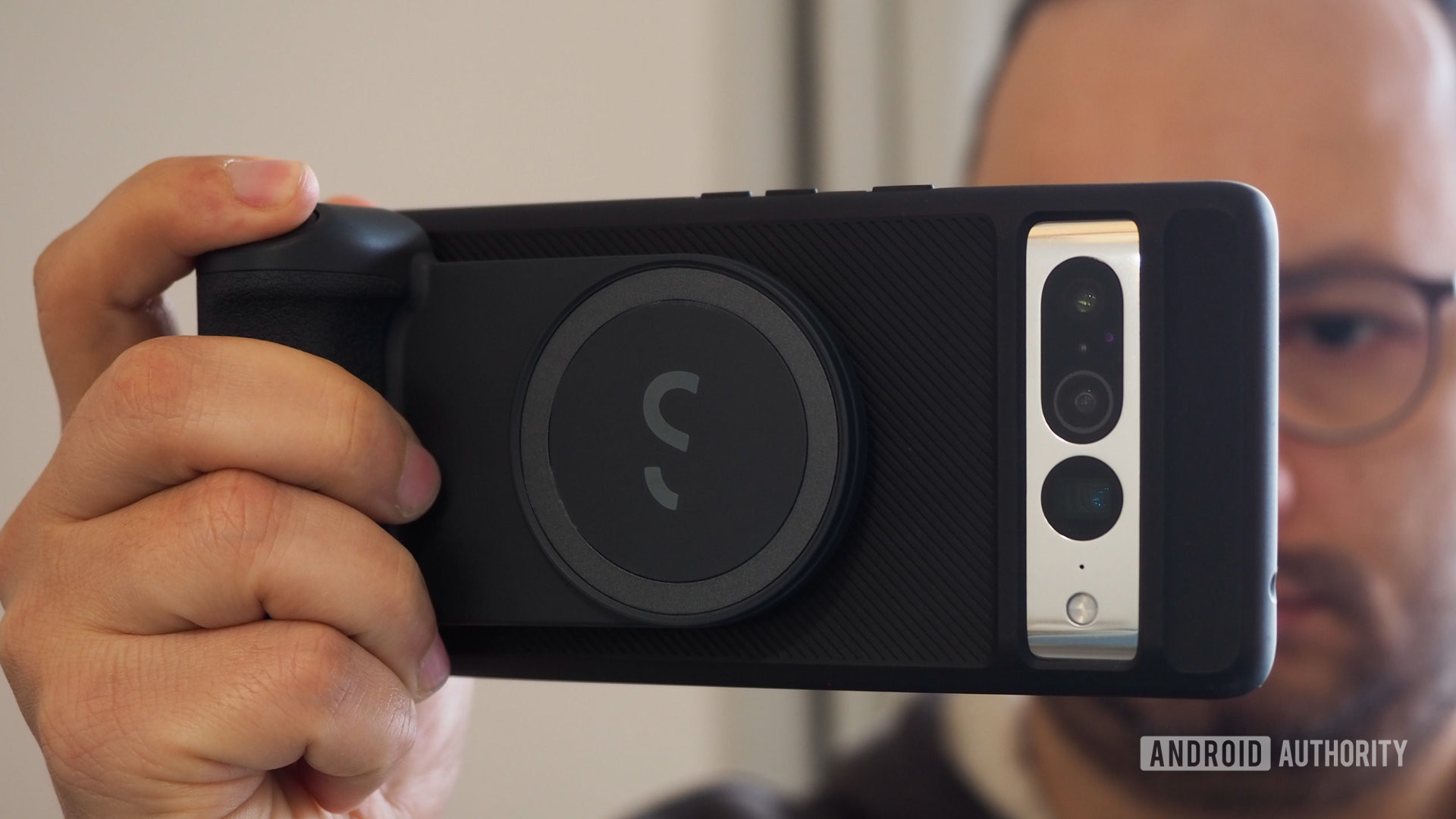 Man holding the ShiftCam SnapGrip which is attached via MagSafe to a Google Pixel 7 Pro with the Moment (M) Force case