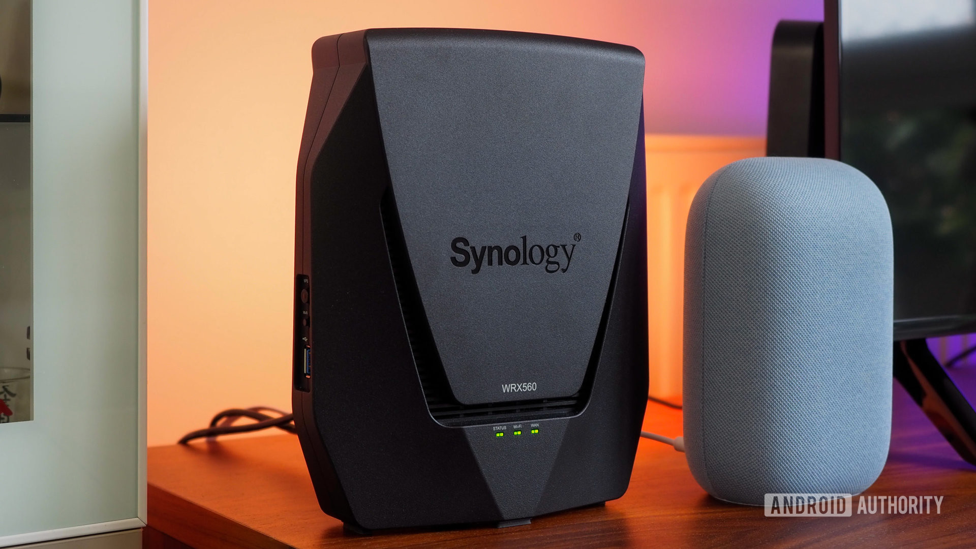 Synology WRX560 router next to a Google Nest Audio with orange and purple light in the background