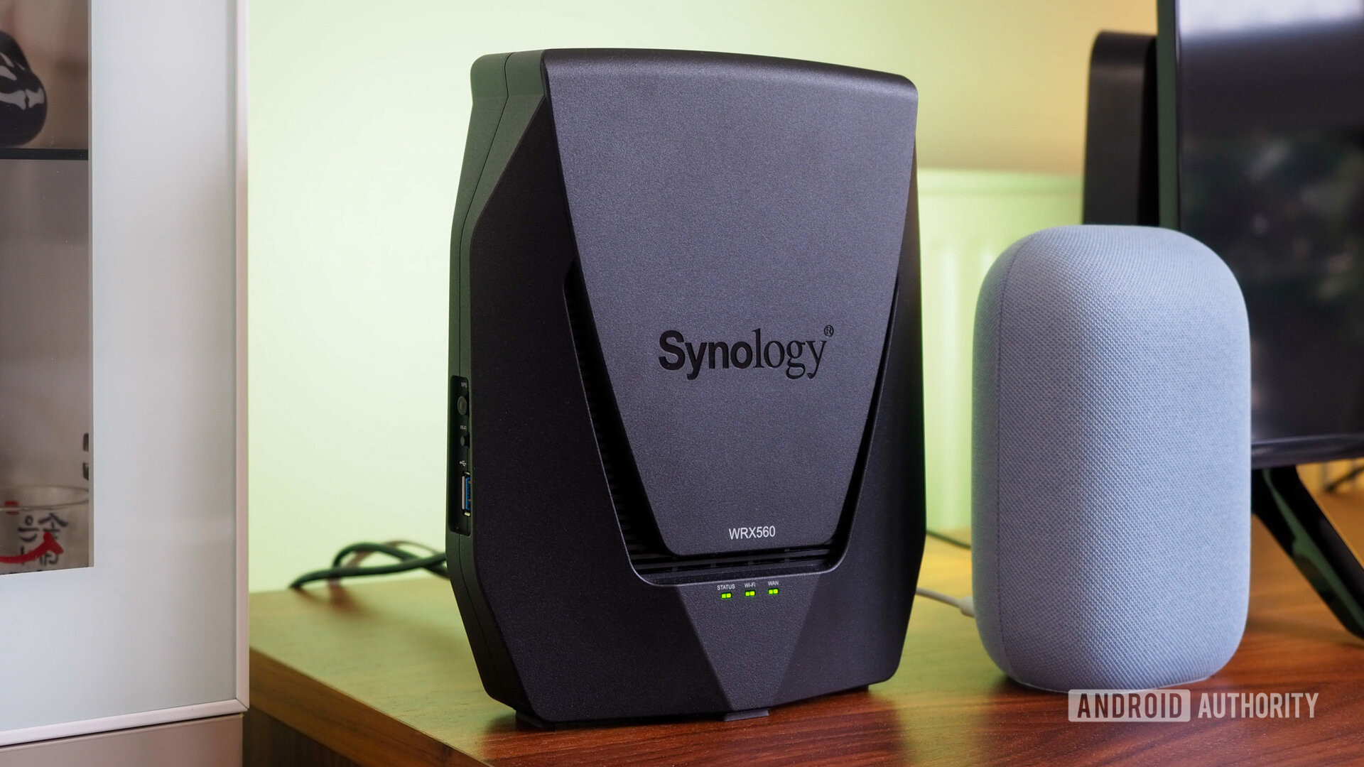Enrutador Synology WRX560 junto a Google Nest Audio con una luz verde de fondo
