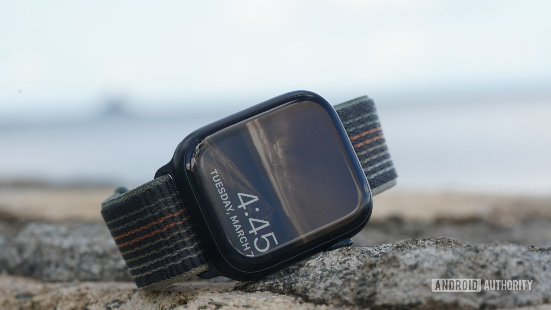 An Apple Watch Series 8 rests on a rock wall displaying its watch face.