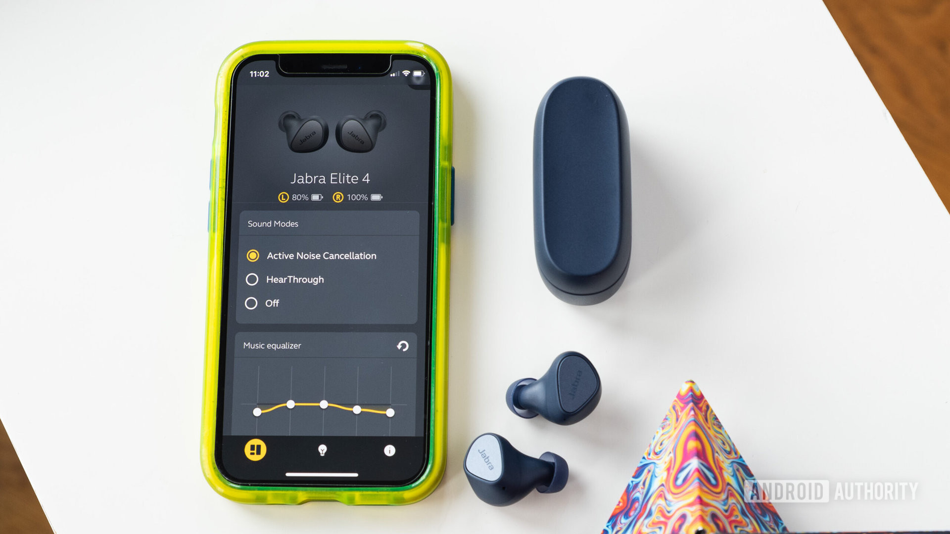 The Jabra Elite 4 wireless noise cancelling earbuds next to an iPhone displaying the MySound+ app.
