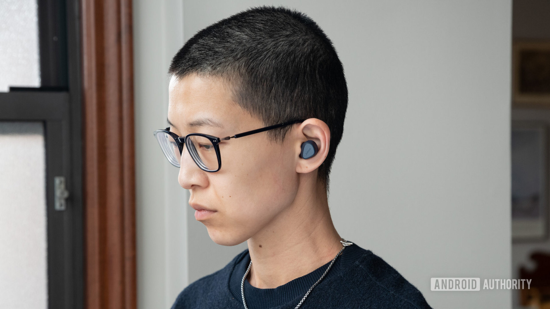 A person wears the Jabra Elite 4 wireless noise cancelling earbuds.