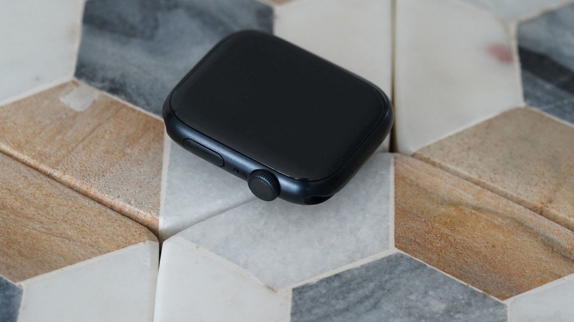 An Apple Watch Series 8 rests on geometric tile.