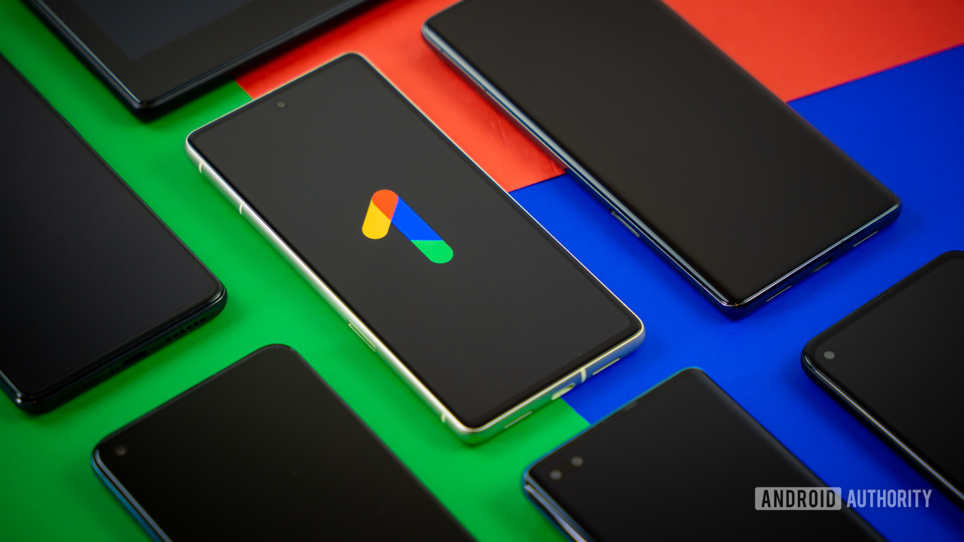 Google One logo on smartphone next to other devices Stock photo 1