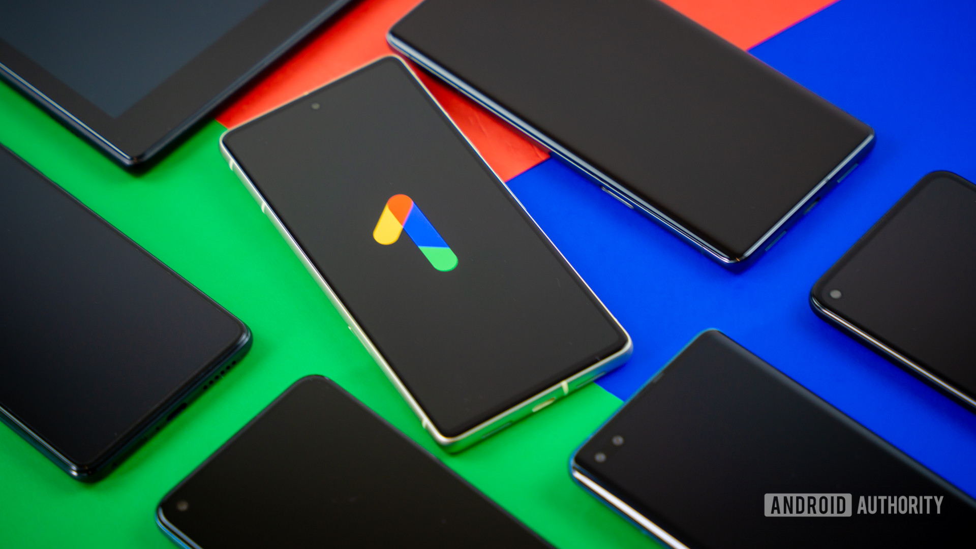 Google One logo on smartphone next to other devices Stock photo 2