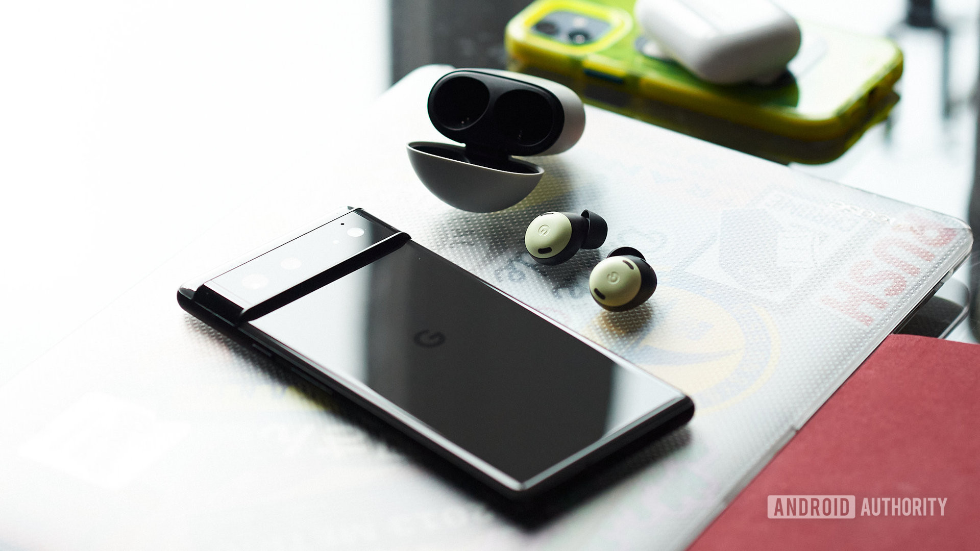 The Google Pixel Buds Pro earbuds outside of the open case and next to a Pixel 6 phone.
