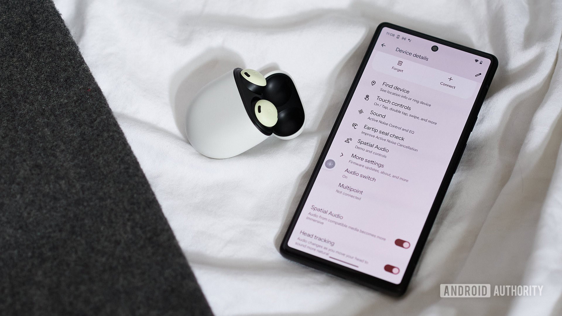 The Google Pixel Buds Pro case and earbuds next to a Pixel 6 that displays Pixel Buds settings.