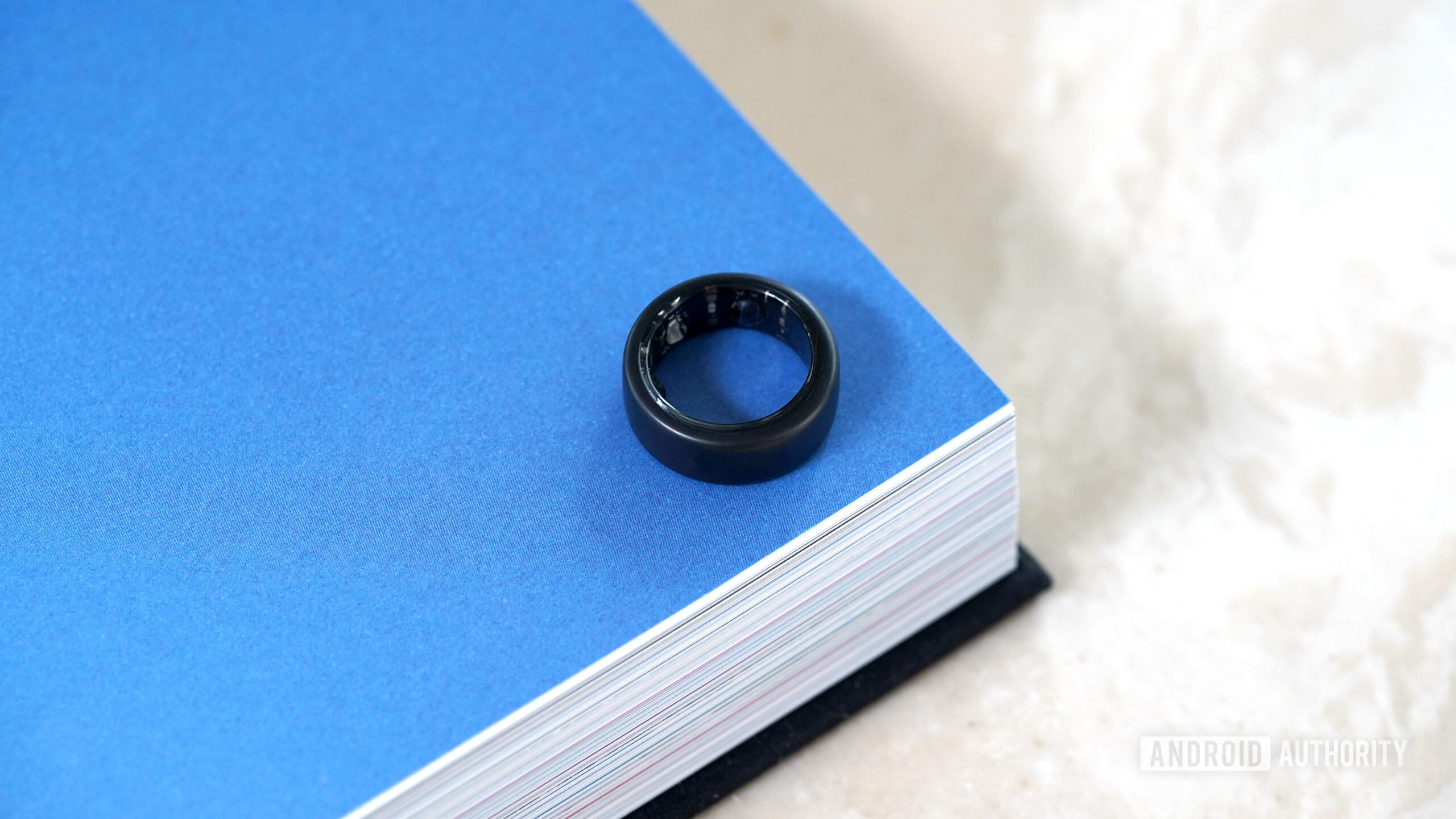 An Oura Ring 3 in Stealth rests flat on a book.
