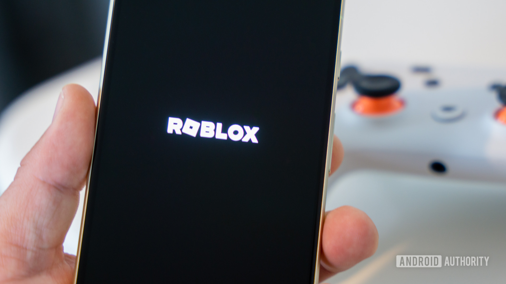 Roblox game logo on smartphone next to controller Stock photo 5