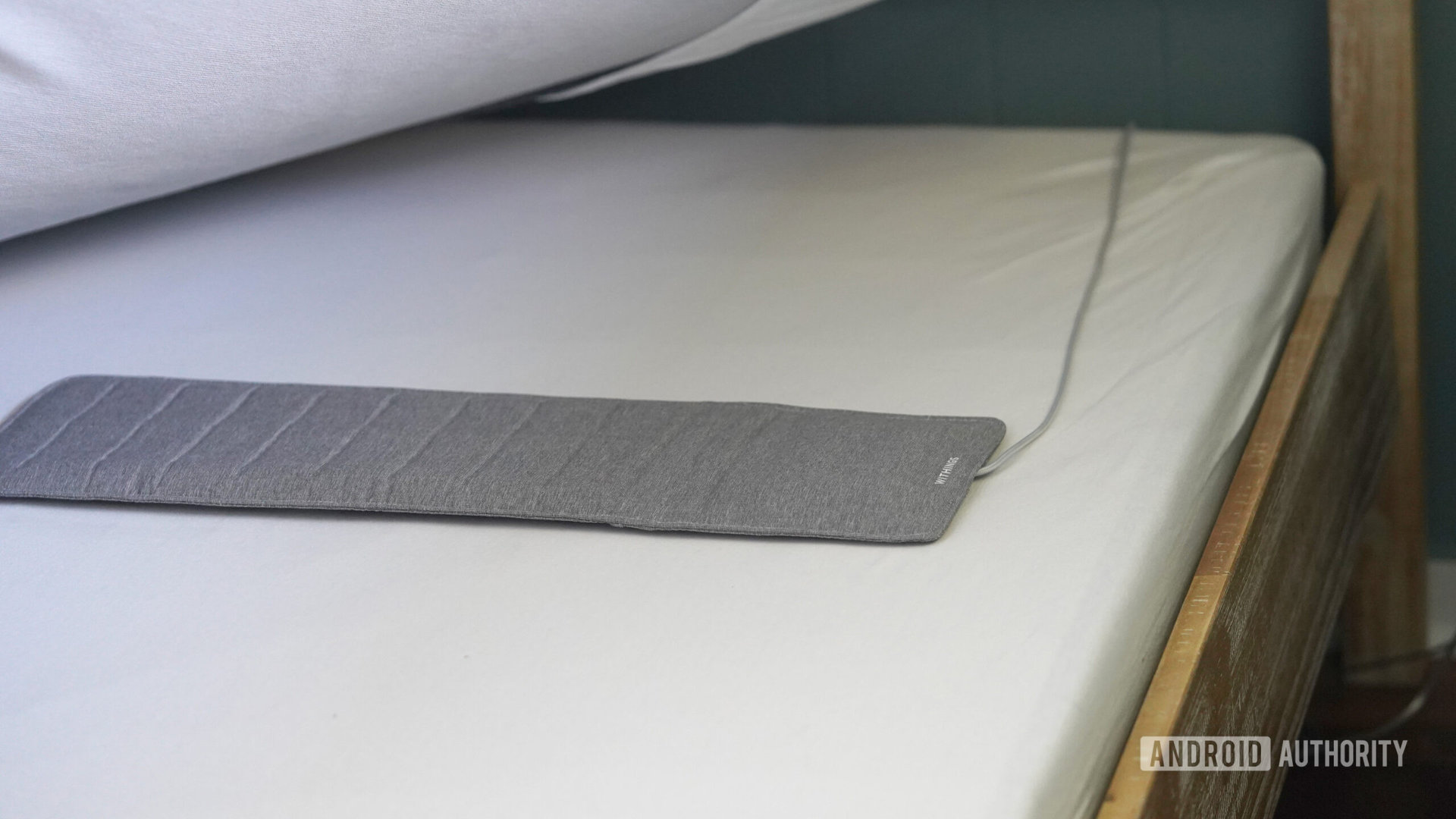 A user installs their mat below their mattress.