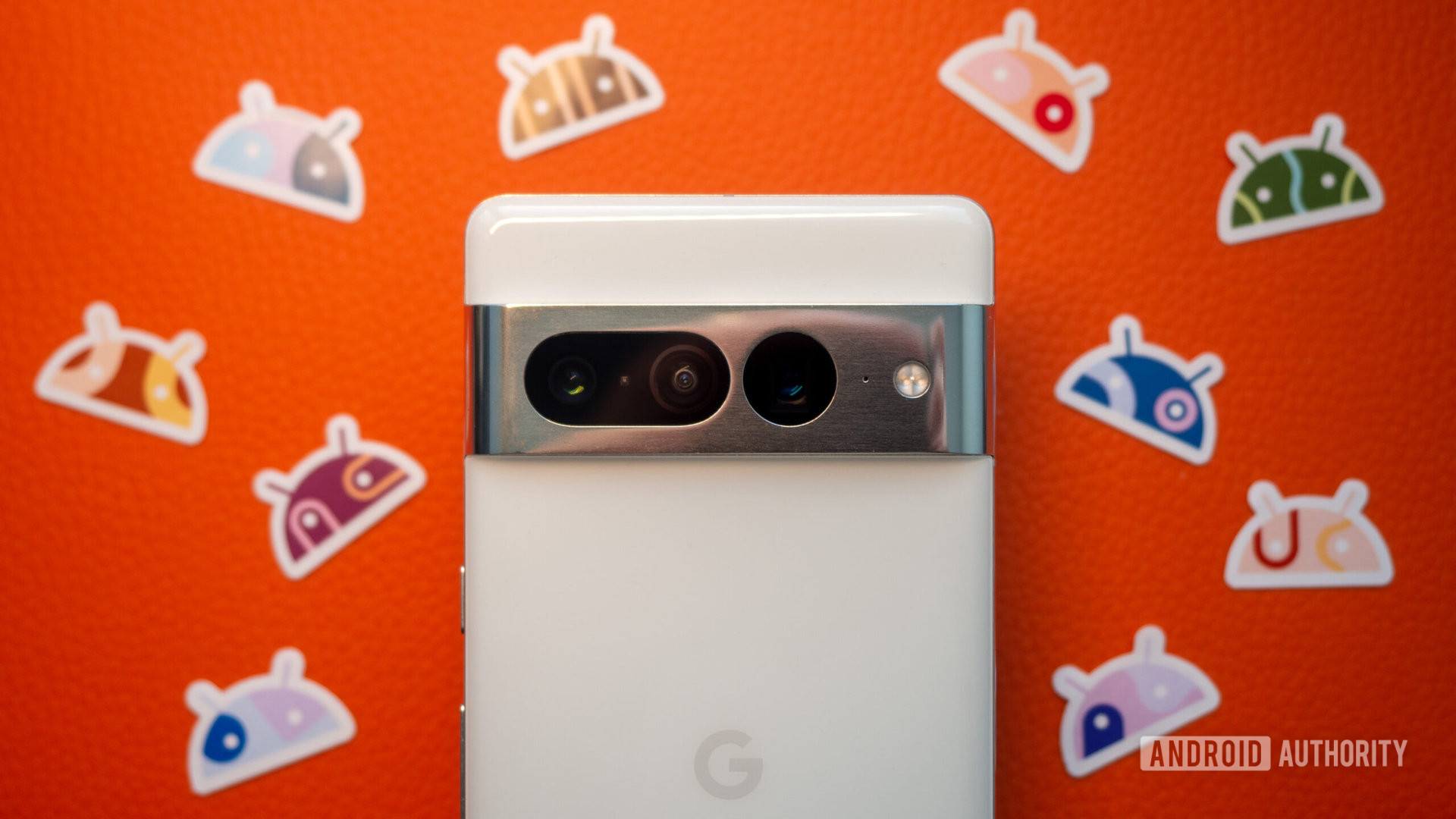 Google Pixel 7 Pro berwarna putih dengan latar oranye dengan stiker Android di sebelahnya