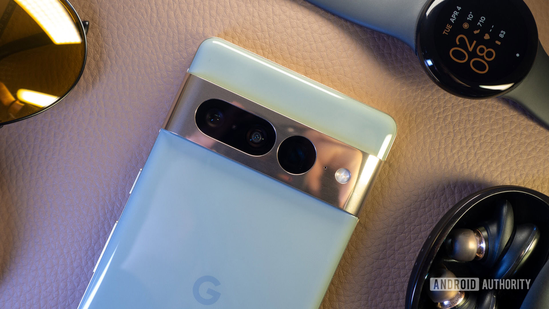 Google Pixel 7 Pro hazel next to Pixel Watch, wireless earbuds, and sunglasses