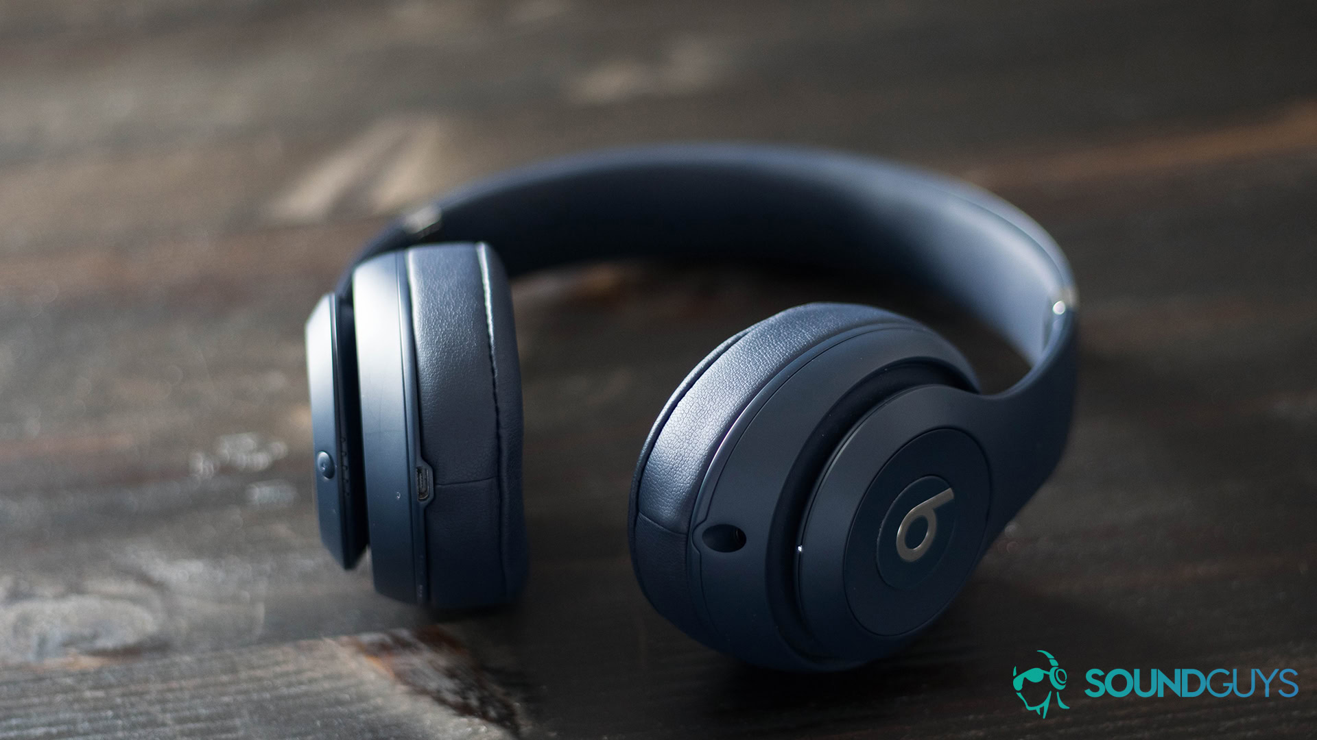 The Beats Studio 3 Wireless headphones in navy blue on a dark wood surface.