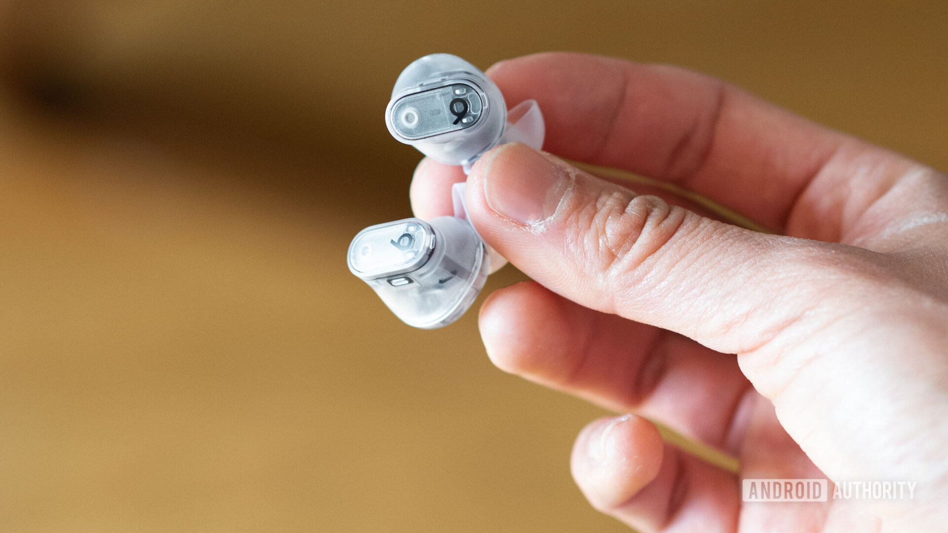 A hand holds the Beats Studio Buds Plus earbuds.