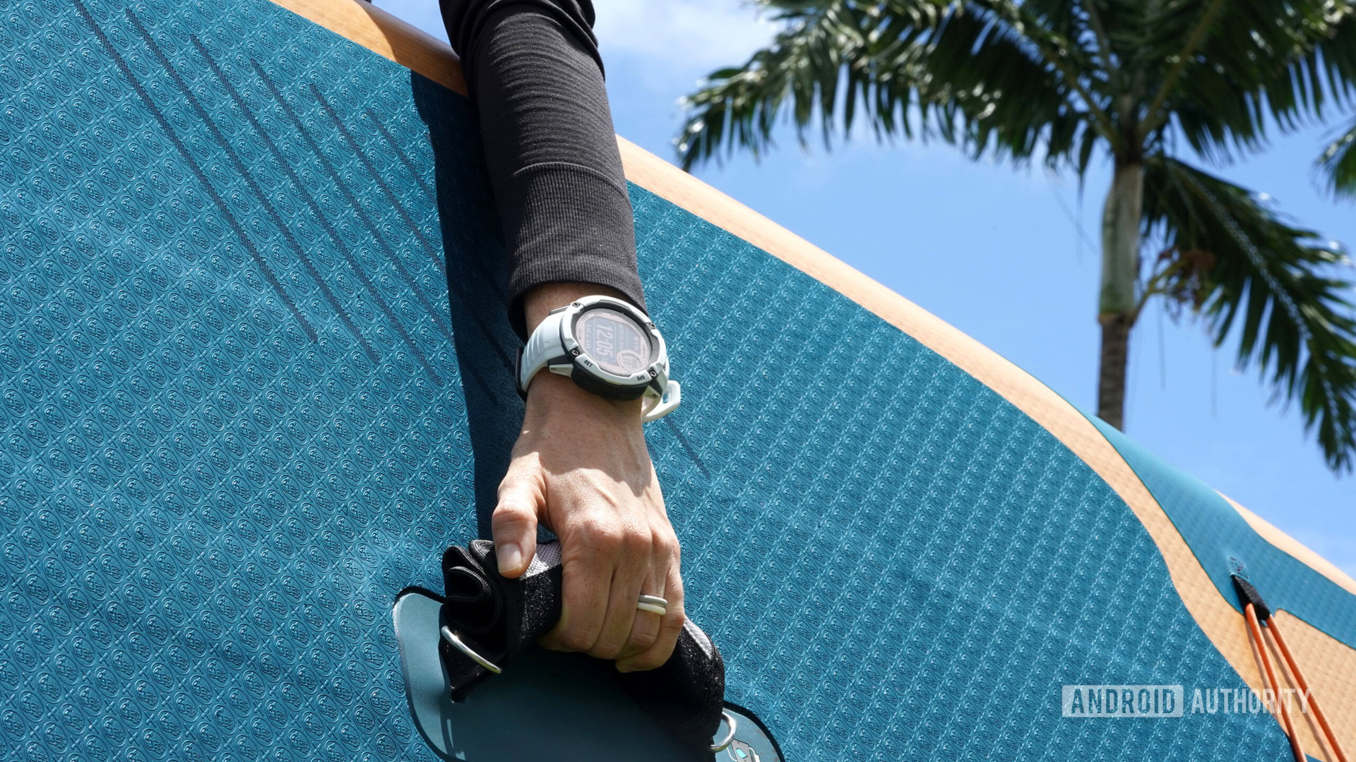 A Garmin Instinct 2X user holds a stand up paddle board.