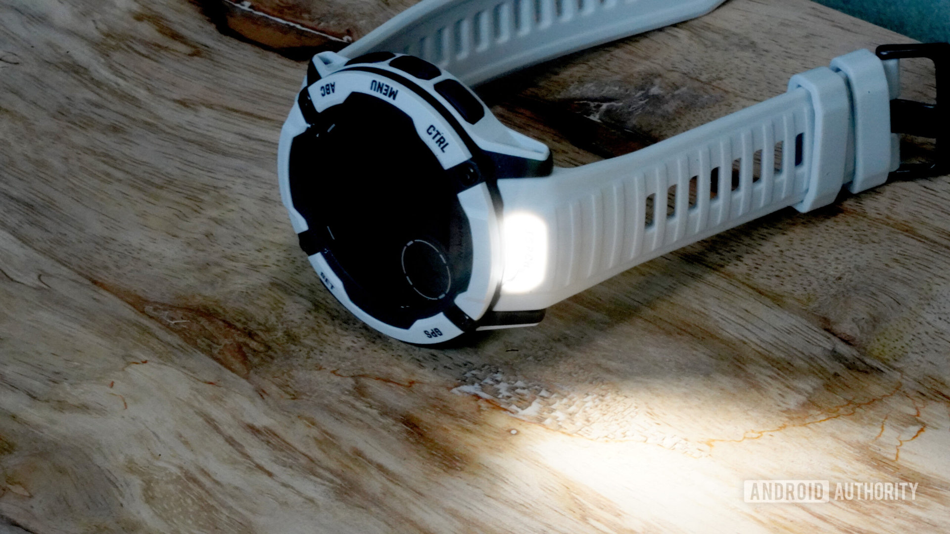 A Garmin Instinct 2X rests on its side with its torch active.