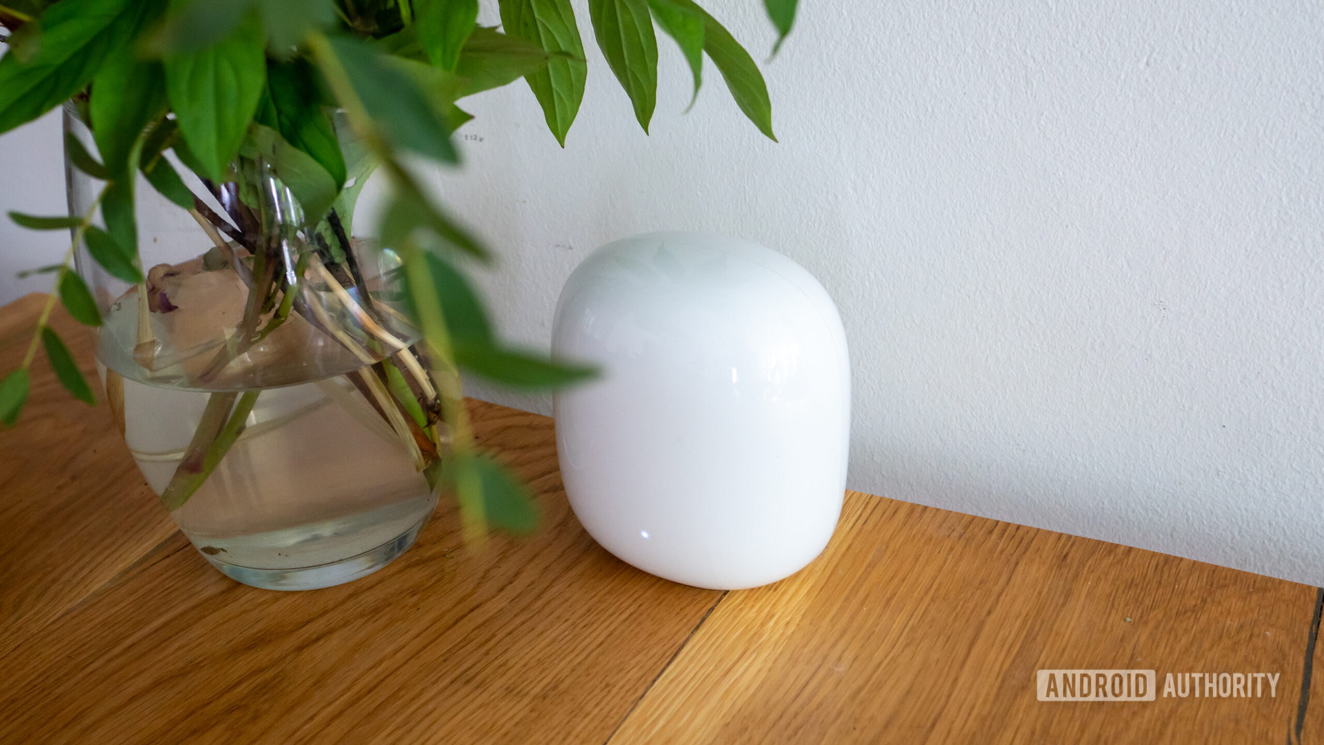 Google Nest Wi Fi Pro router elevated view on wooden table next to vase