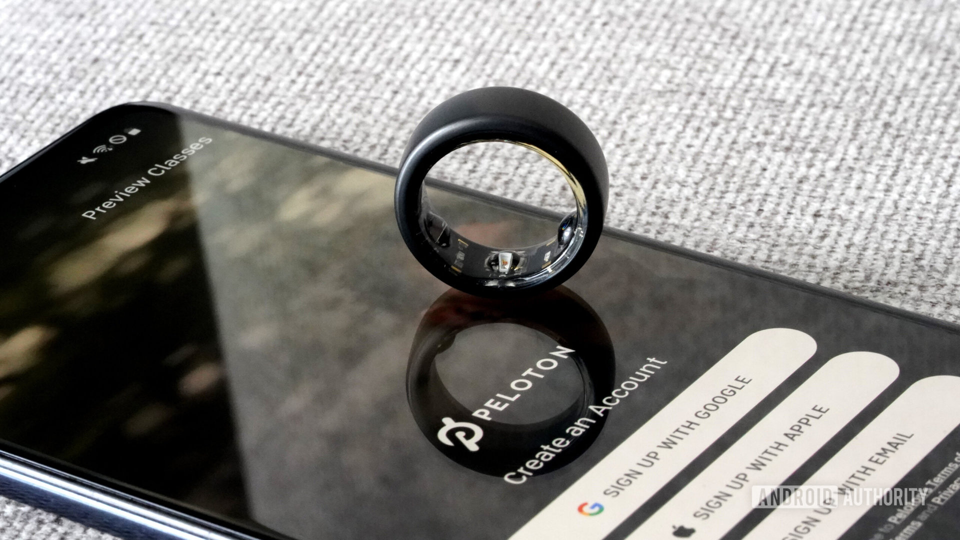 An Oura Ring 3 rests on a smartphone with the Peloton app displayed.