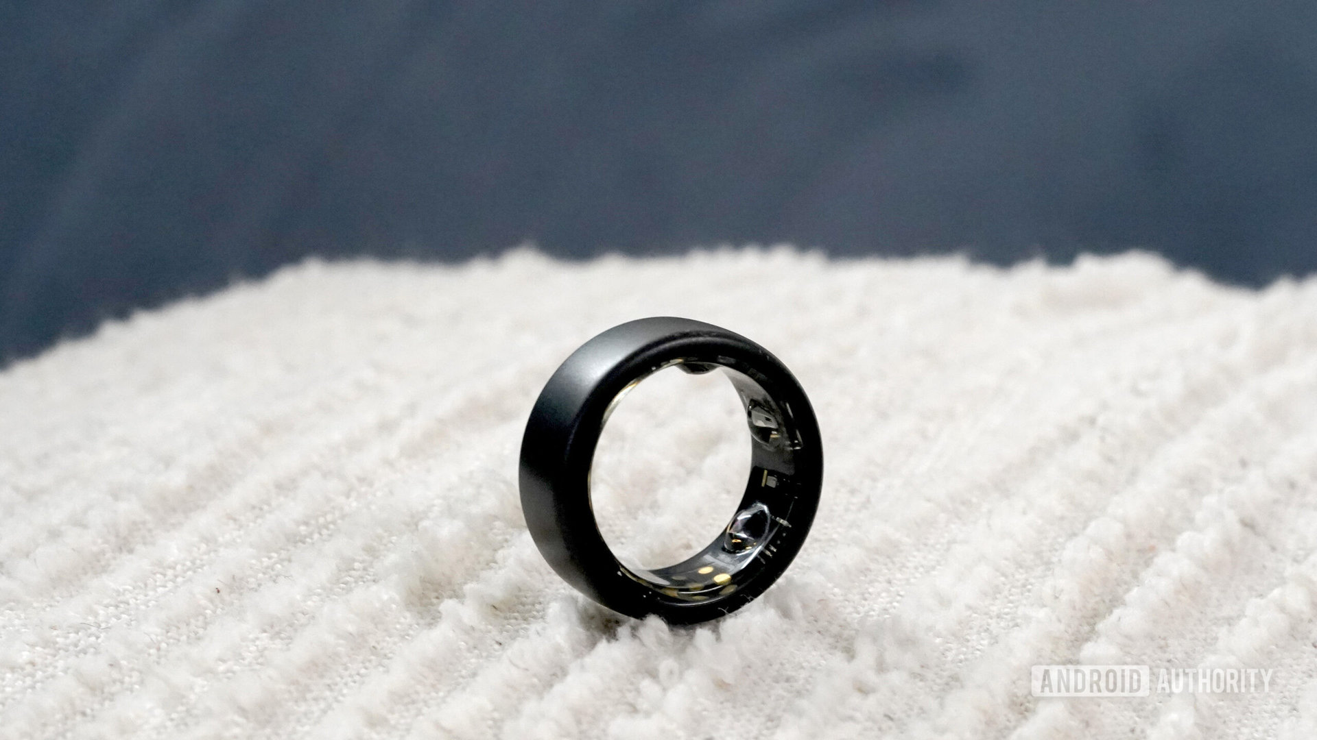 An Oura Ring 3 rests on a pillow.